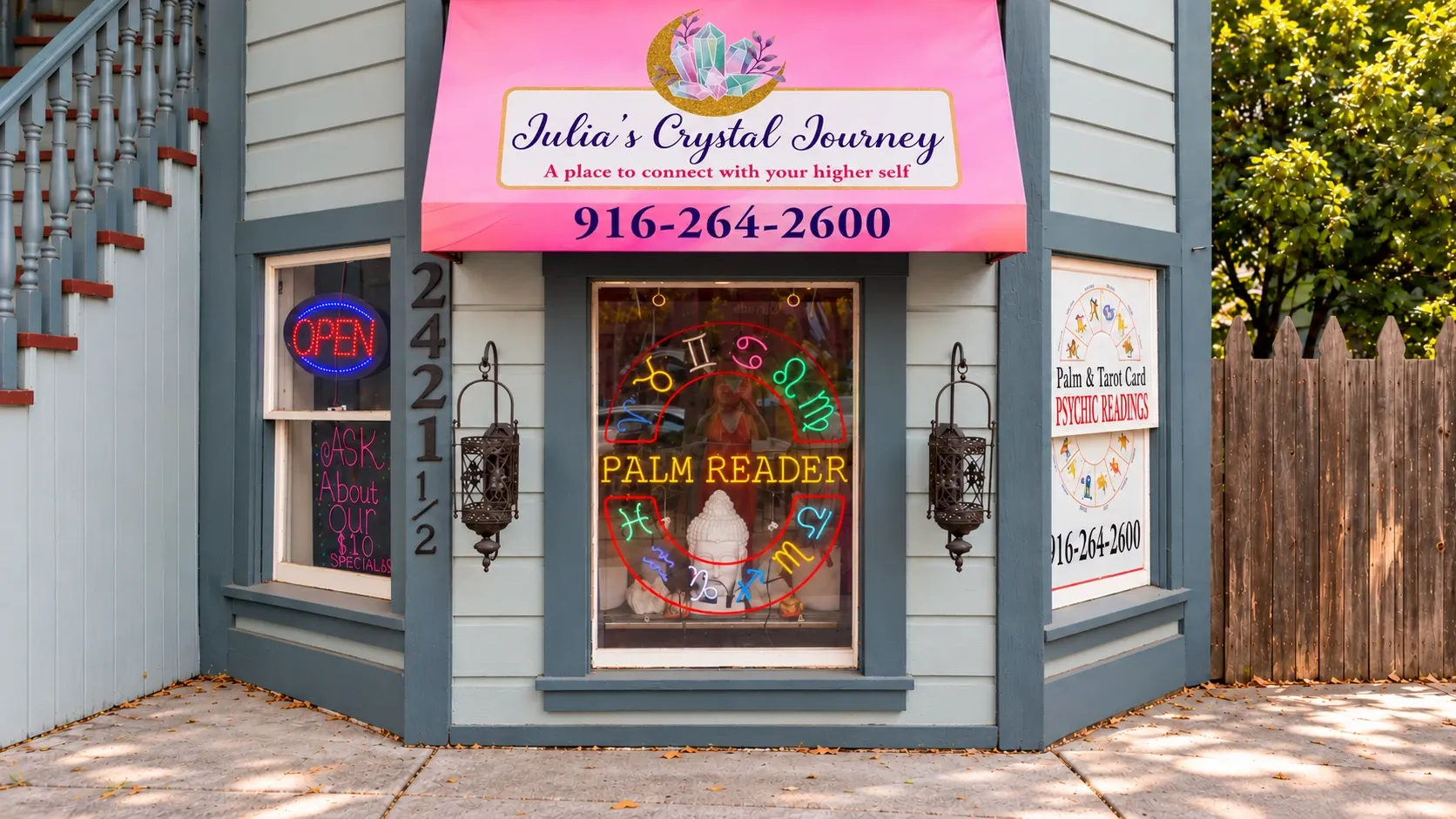 The storefront of Julia’s Crystal Journey on J Street, with a pink awning and a neon Palm Reader sign in the window