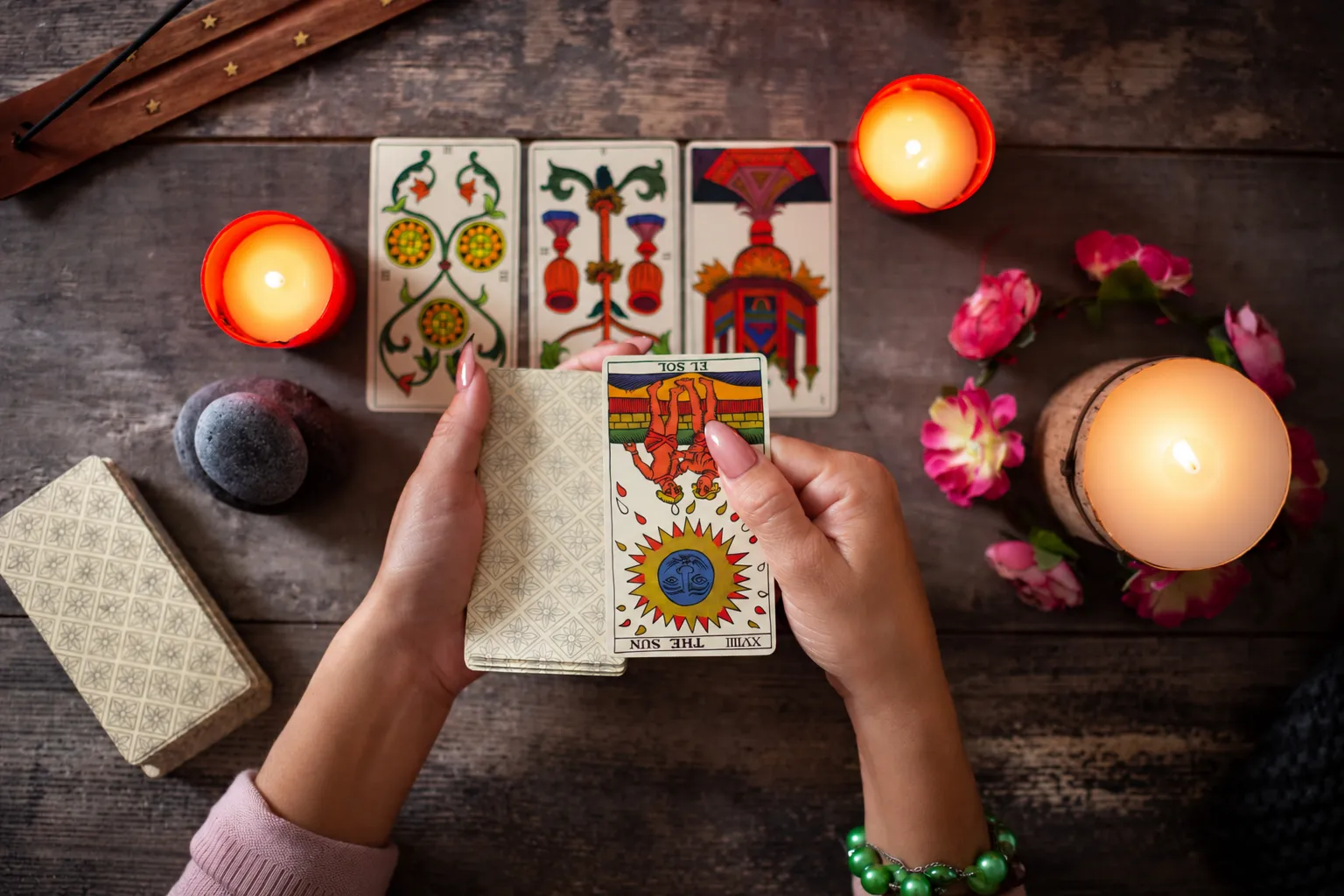 A hand pulling the Sun card from a tarot deck above a three card spread