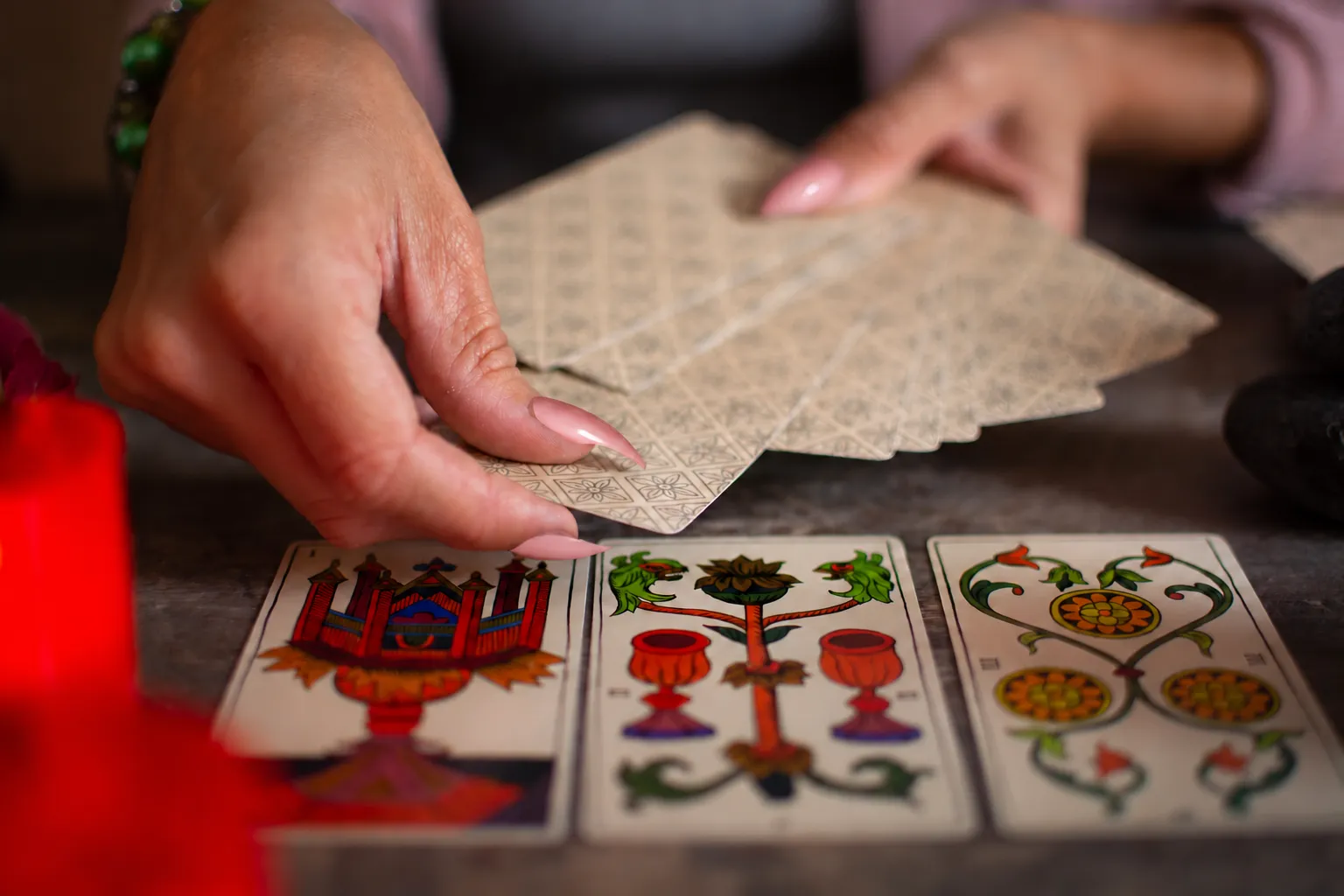 A reader's hand laying a tarot card down in front of a row of three face-up cards